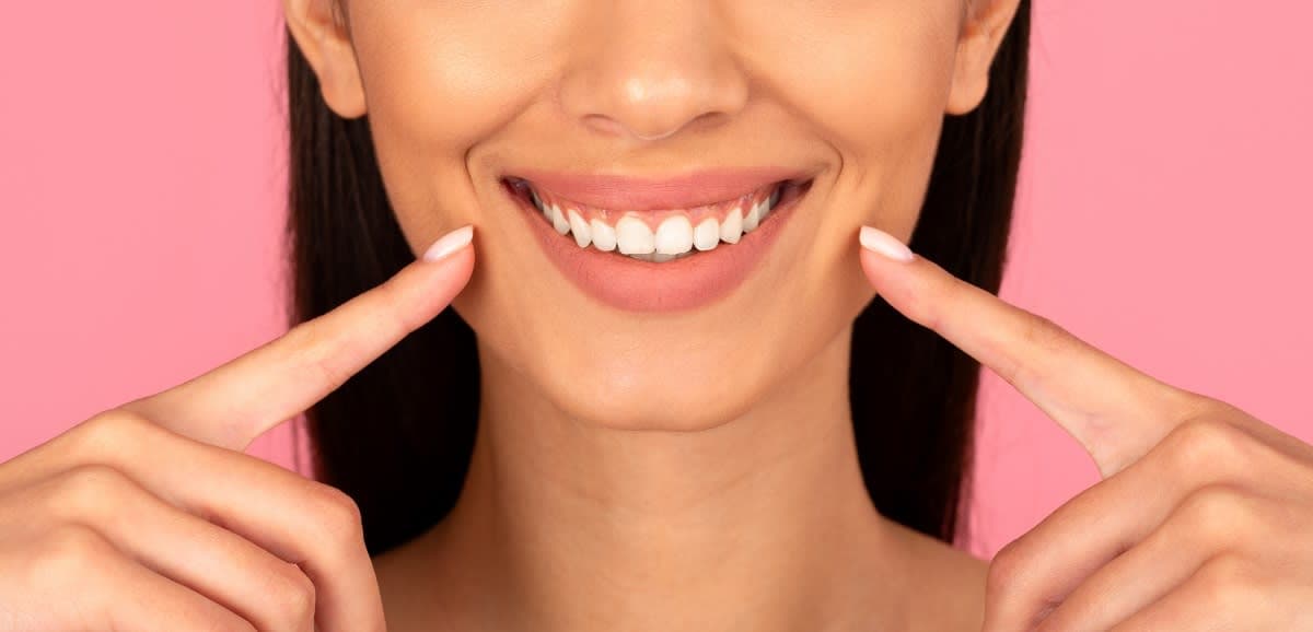 Patient holding their final clear aligner tray beside a retainer case at a post-treatment dental appointment